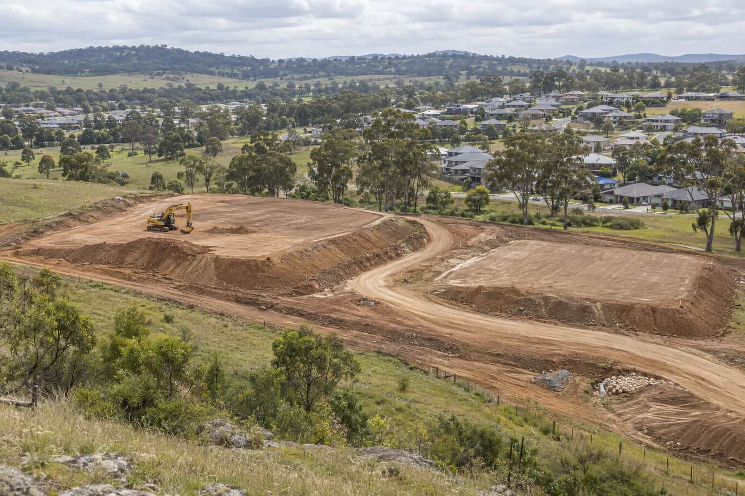 Illustrative Campbelltown civil contractor earthworks stages beside housing and eucalyptus-covered hills in Macarthur, NSW, Australia