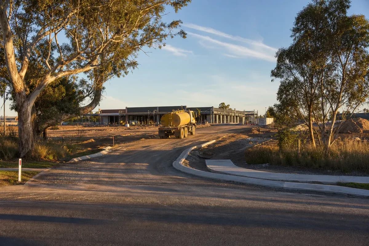 NSW commercial site entry with kerb return and water cart on access formation beside eucalypts