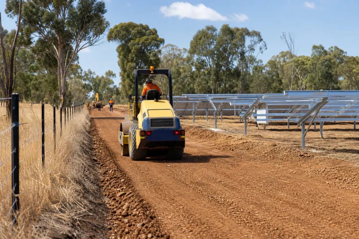Renewable energy access roads NSW gravel formation with roller and tipper beside solar farm civil works NSW array rows