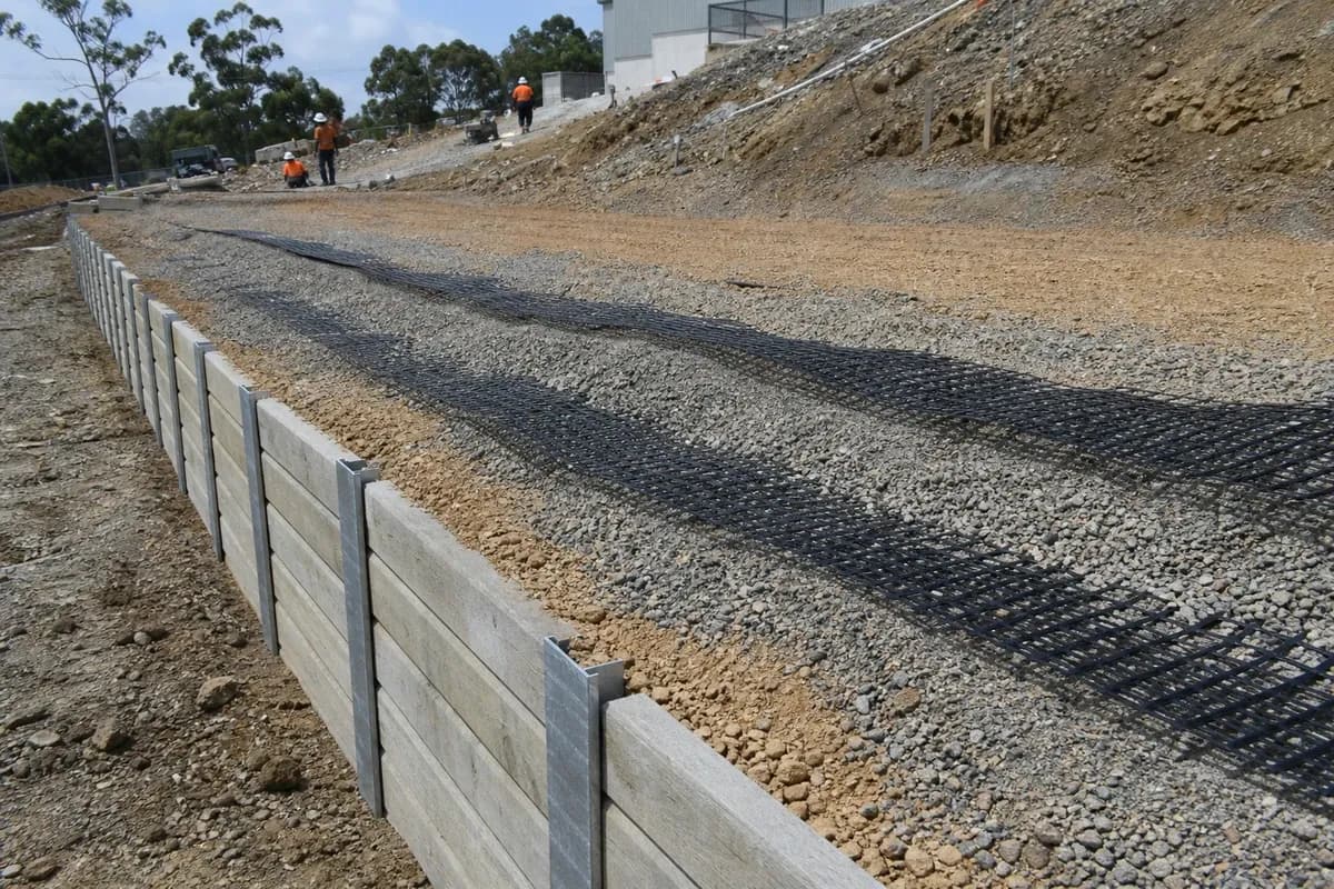 Structural civil works NSW retaining wall construction with geogrid layers and compacted backfill on a sloped industrial pad