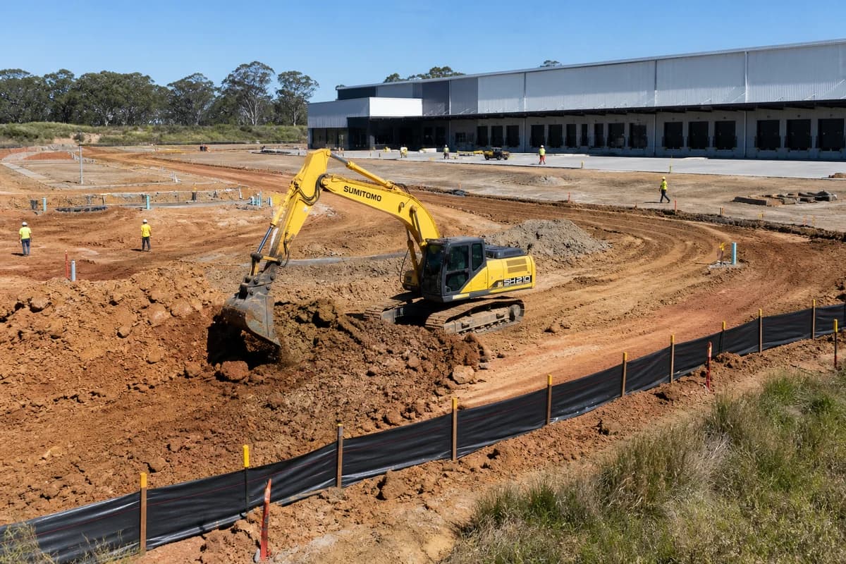 Warehouse civil works NSW dock-court earthworks with yellow excavator forming a logistics apron on a New South Wales industrial estate